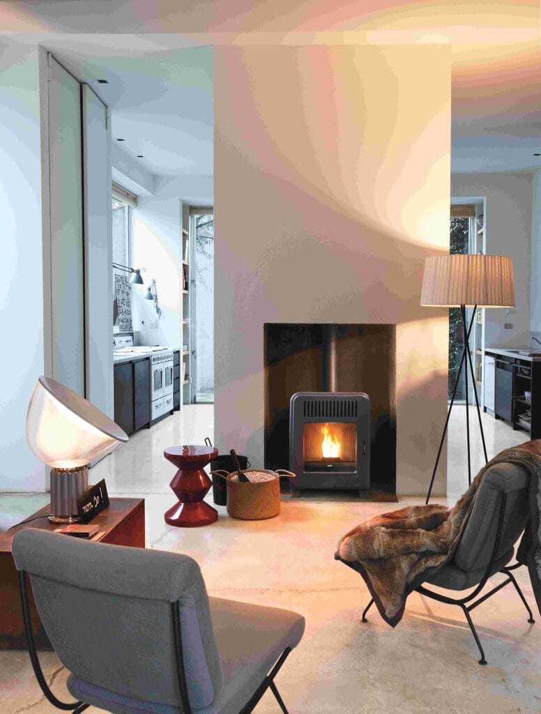 A modern living room featuring a fireplace, two chairs, and a lamp.