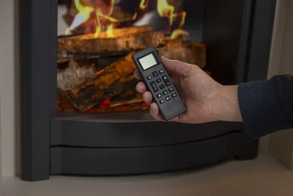 A hand holds the remote for the Parkray Aspect 5 Pure Flame Electric Stove as realistic flames and glowing logs create a warm, fireside look.