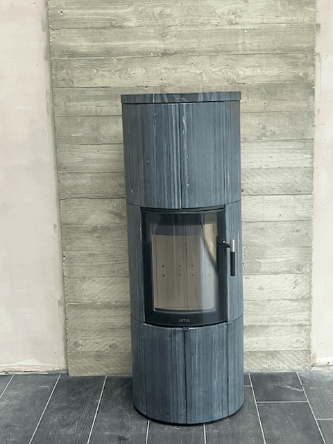 Tall Lotus Maestro 152 wood-burning stove with Indian Night Stone cladding and a glass-fronted firebox indoors